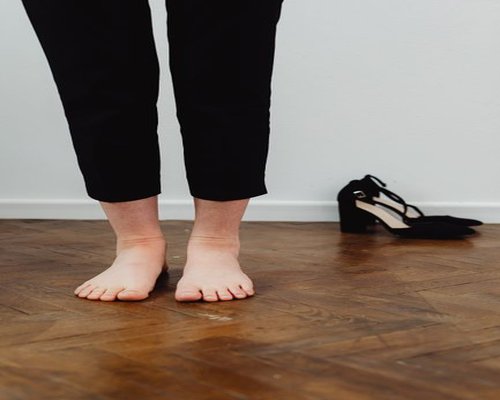 A person removing professional office footwear at home, observing transient soft impressions on the skin