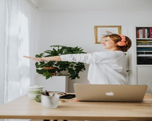 Person stretch gently beside a bright workspace window highlighting routine workspace wellness choices